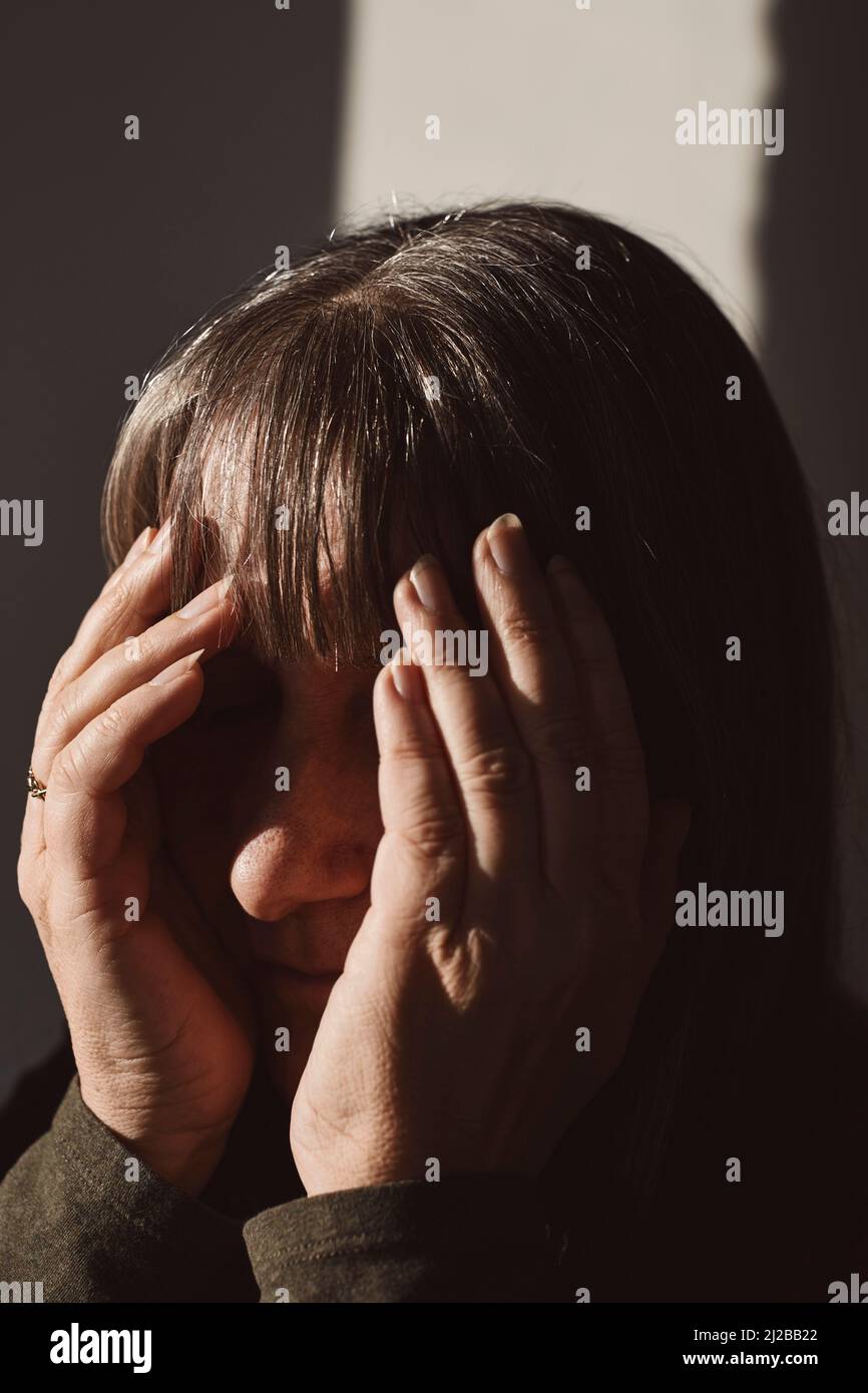 Mature woman covering face in studio Stock Photo
