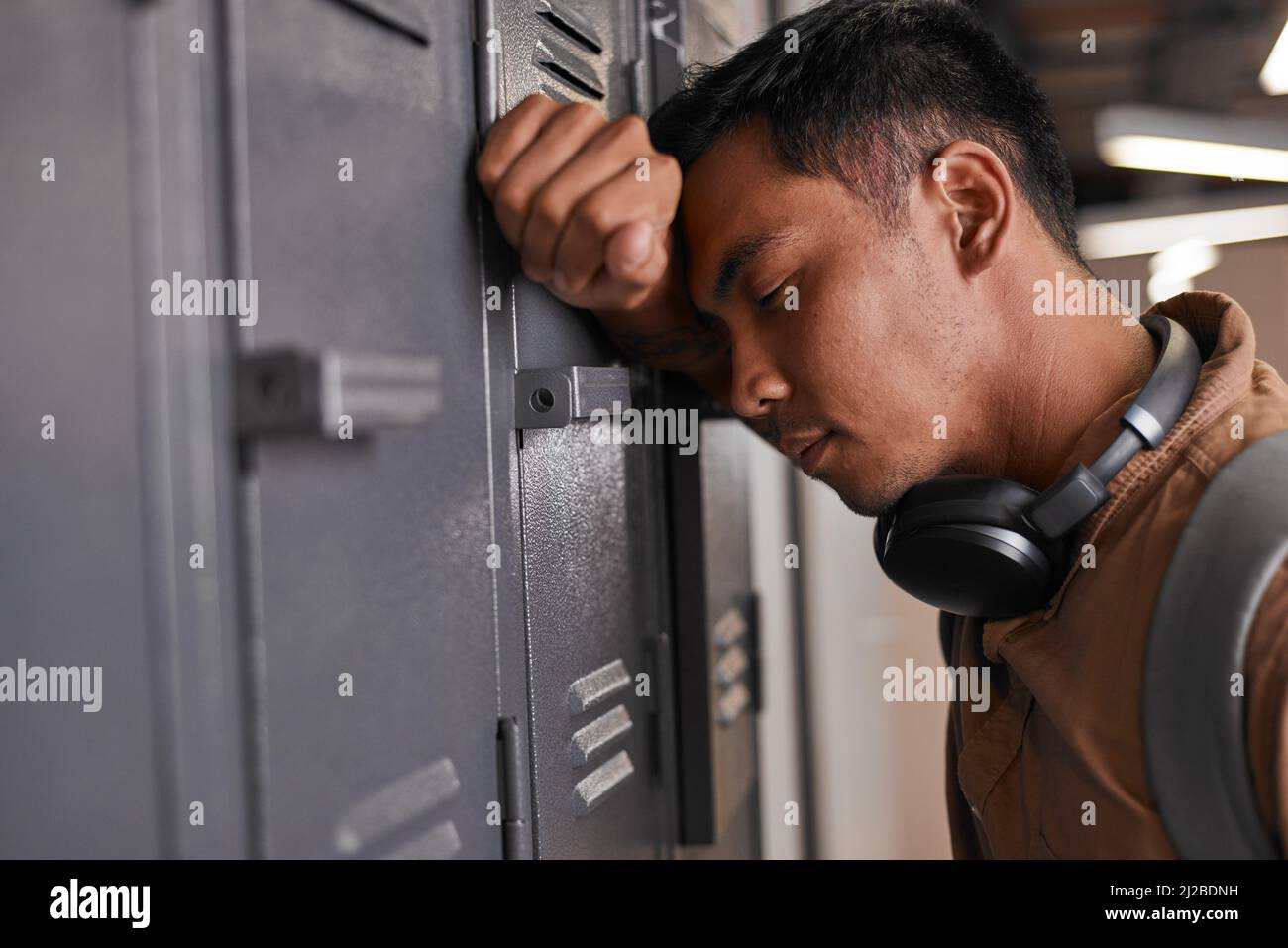 A student leans against campus lockers after getting bad news Stock Photo