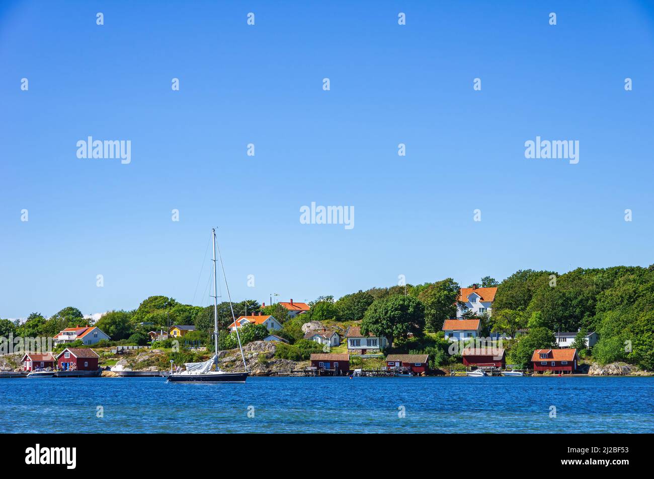Picturesque coastal landscape with sailboat and boat sheds, South coast of North Koster Island, Bohuslän, Västra Götalands län, Sweden. Stock Photo