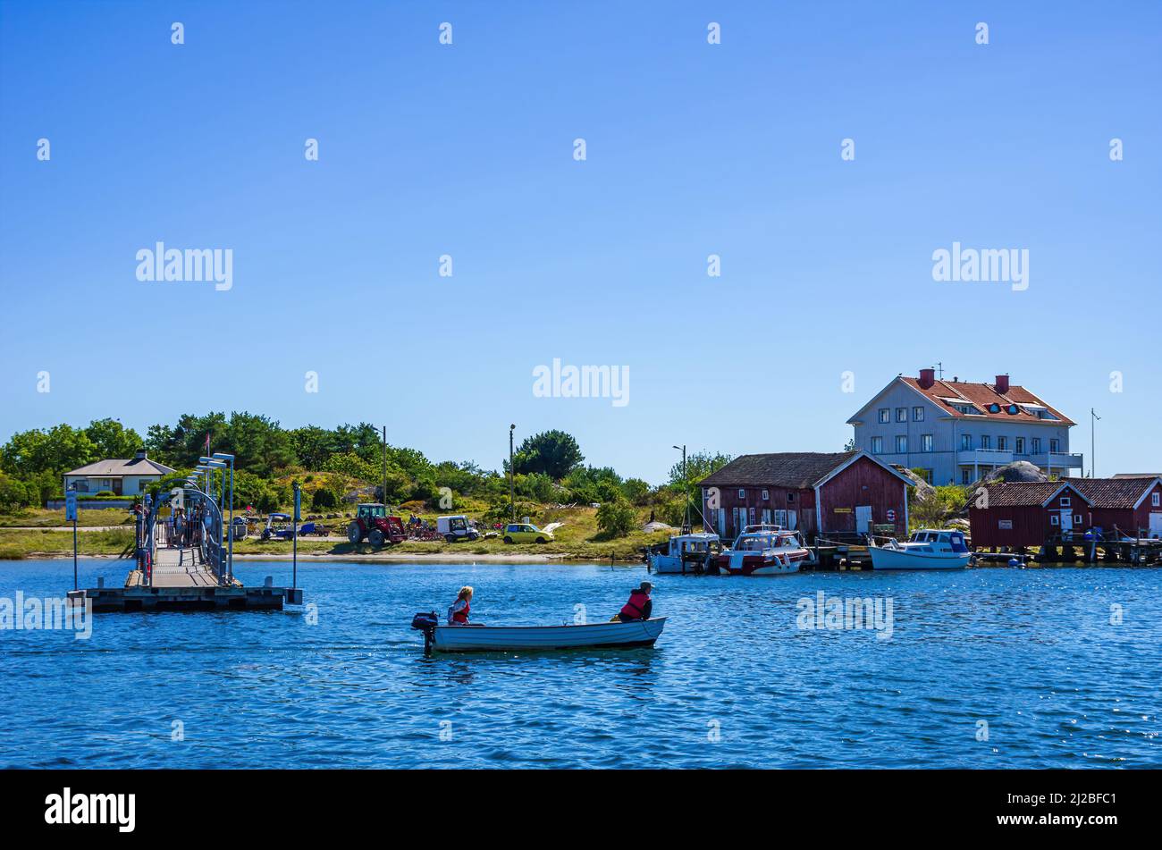 North Koster Island, Bohuslän, Västra Götalands län, Sweden: A motorized boat passes by while tourists wait at the ferry landing on South Koster. Stock Photo