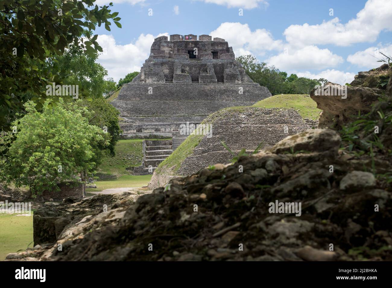 Sunlit pyramid 'El Castillo' behind smaller Maya ruins at the archeological site Xunantunich near San Ignacio, Belize Stock Photo