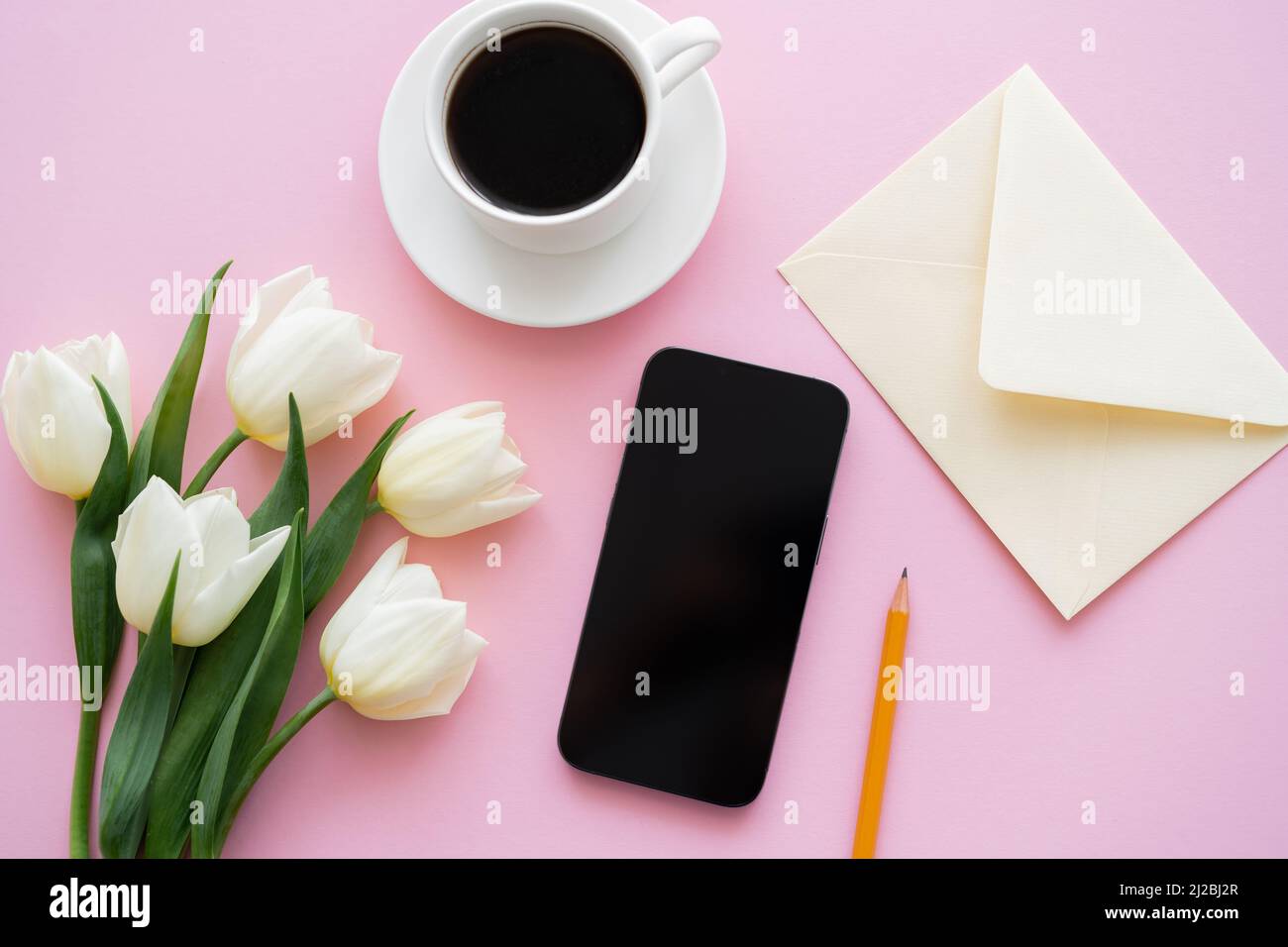 top view of white tulips near smartphone with blank screen and cup of ...