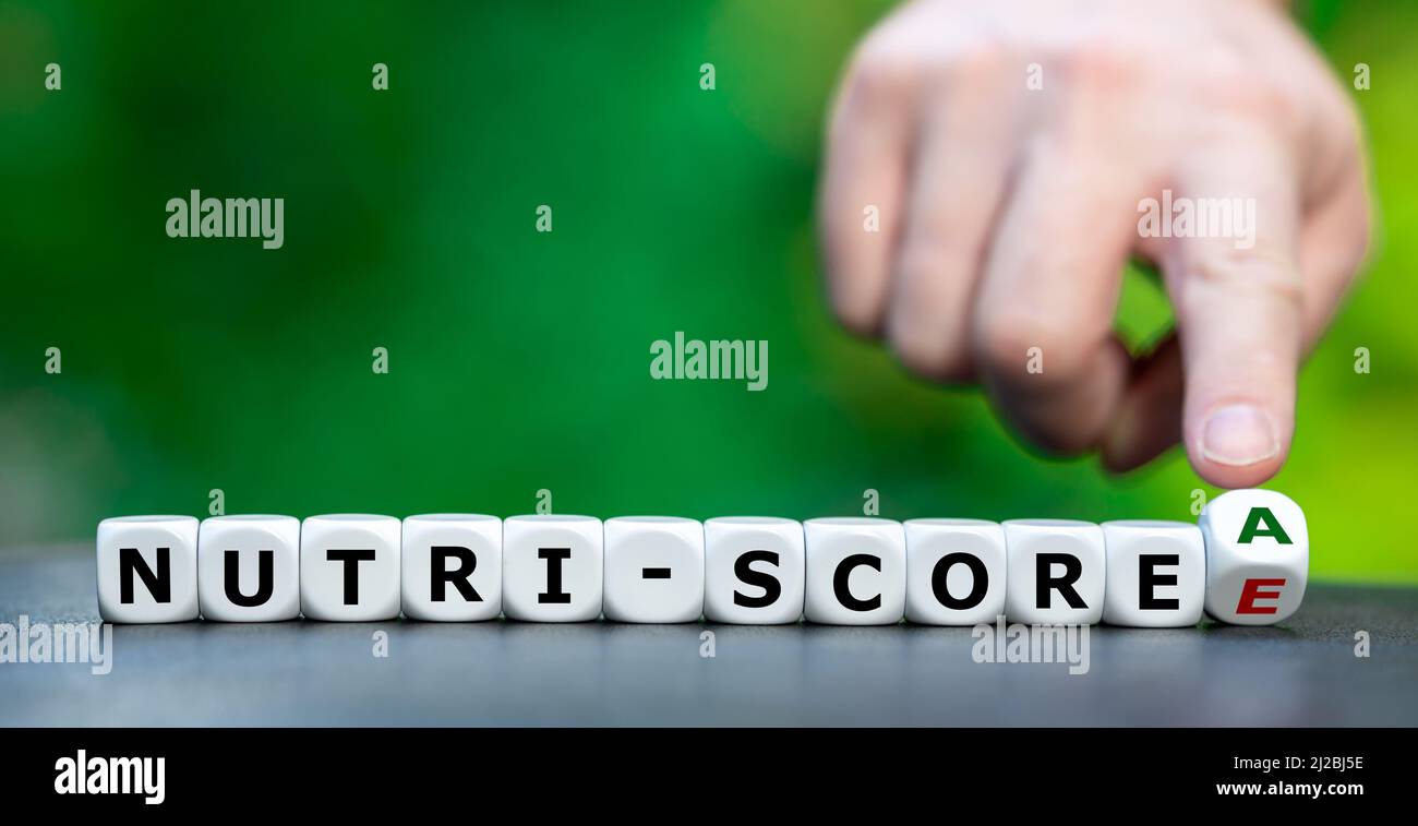 Hand turns dice and changes the expression 'nutri-score E' to 'nutri-score A'. Stock Photo