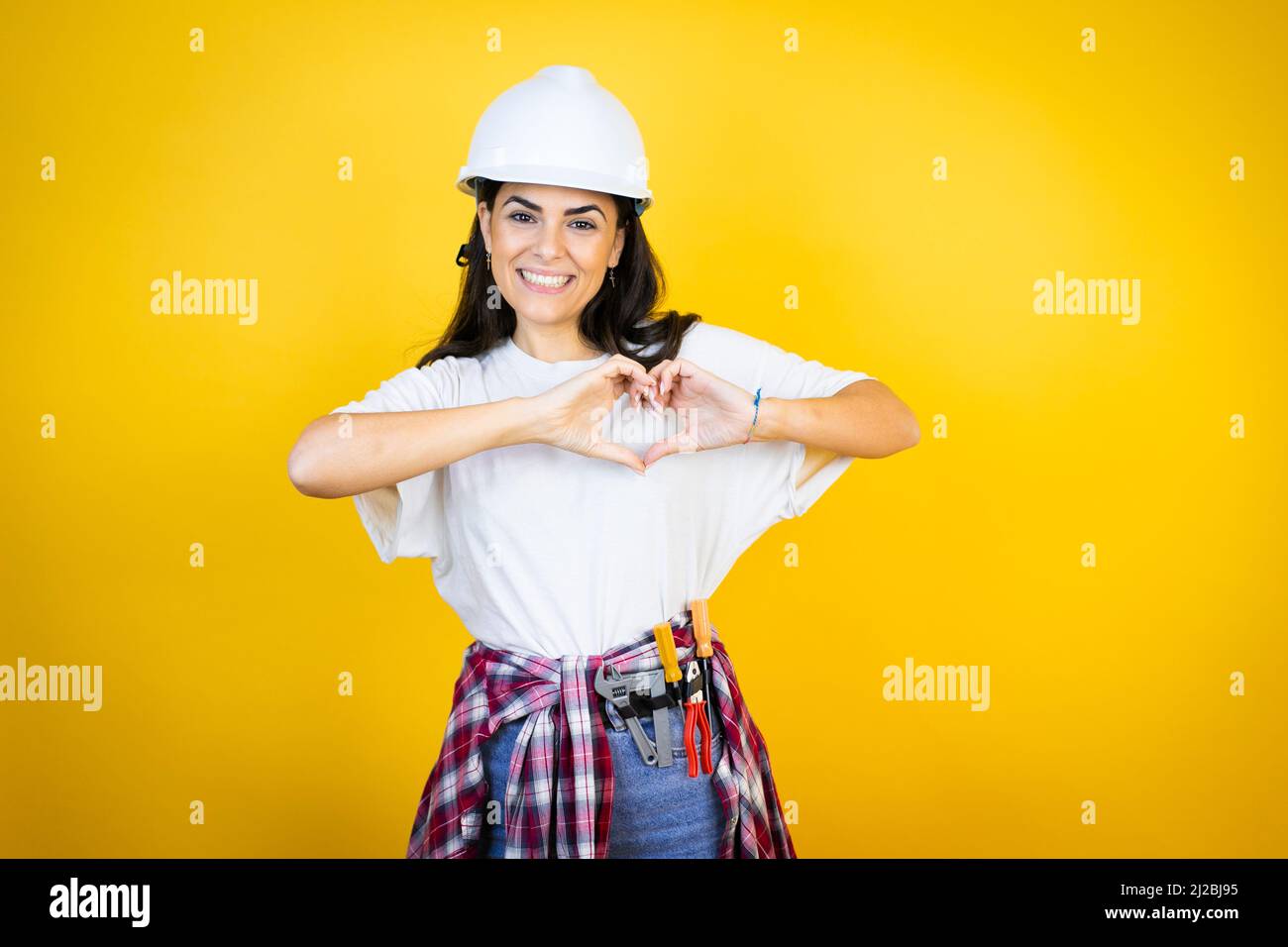 Young caucasian woman wearing hardhat and builder clothes over isolated