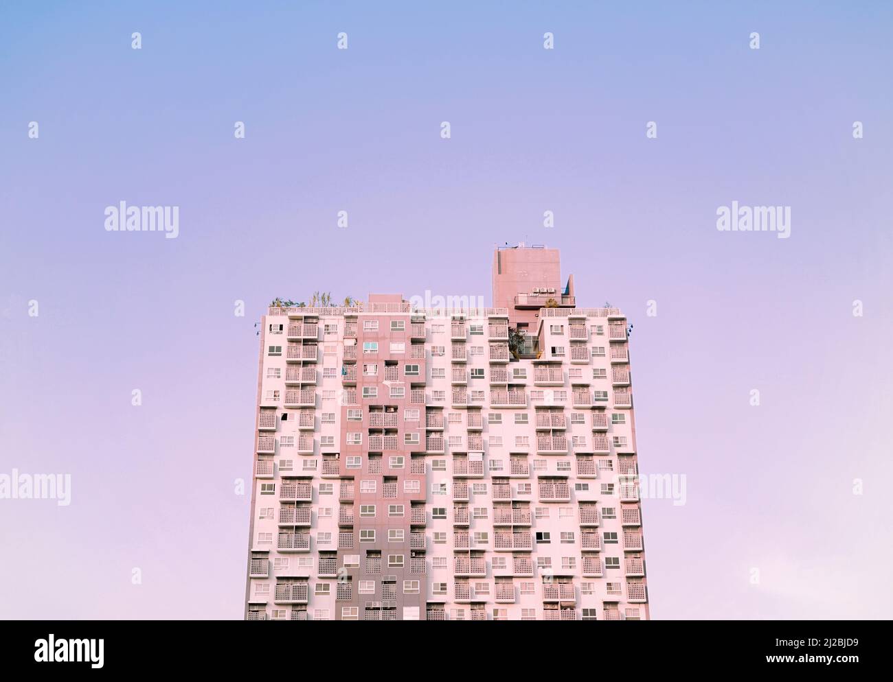 Urban condo, modern flat cosmopolitan residential building structure against pastel lavender purple blue gradient skyline background. Stock Photo