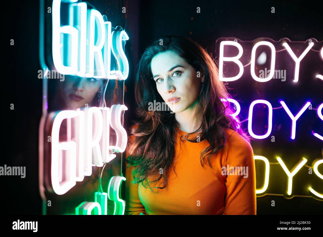 Portrait of brunette caucasian girl with long hair, next to a colourful neon light Stock Photo
