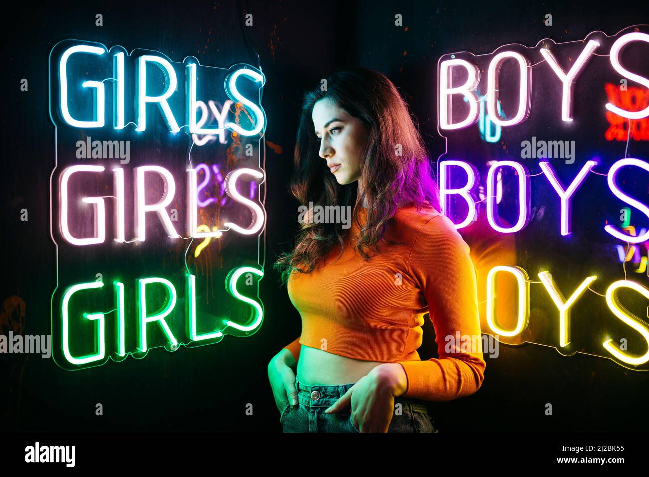Portrait of brunette caucasian girl with long hair, next to a colourful neon light Stock Photo