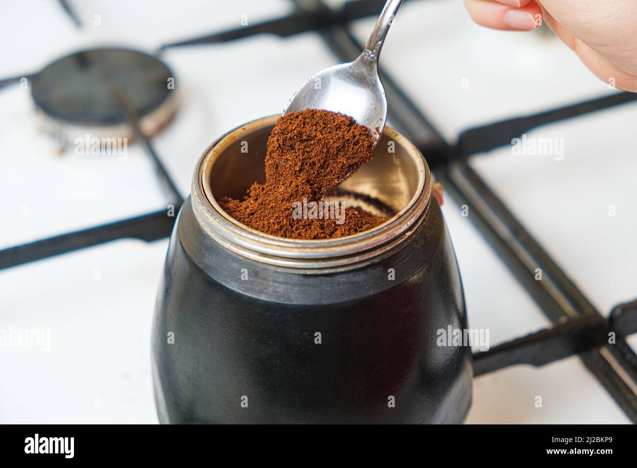 The process of pouring ground fresh coffee into a geyser coffee maker