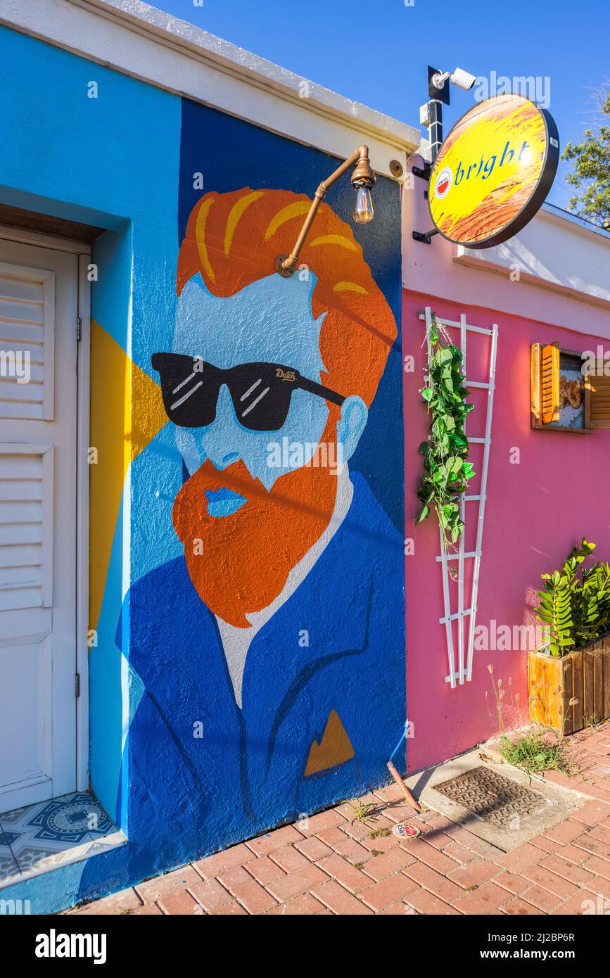 Portrait of a guy with orange hair and beard wearing black sunglasses painted on a wall of a bar with a Amstel bright sign in Willemstad, Curacao Stock Photo