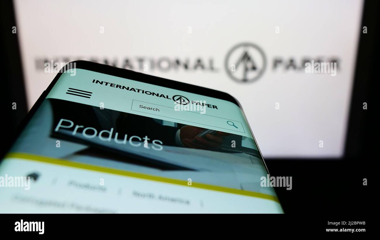 Mobile phone with webpage of American company International Paper Company (IP) on screen in front of logo. Focus on top-left of phone display. Stock Photo