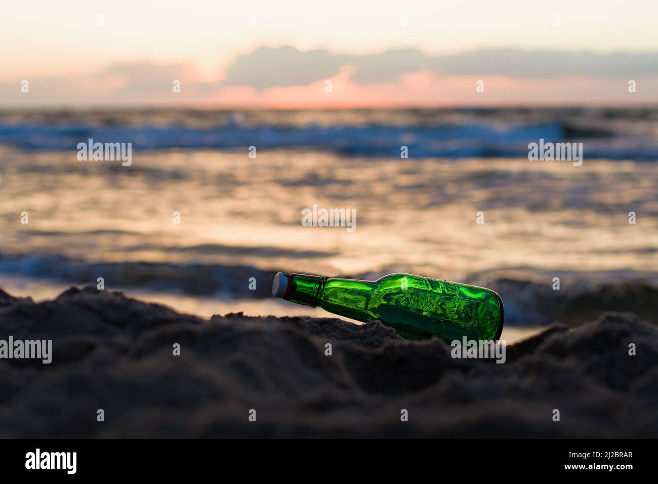 Message in the bottle washed ashore against soft waves. Dreamy ideas concept Stock Photo