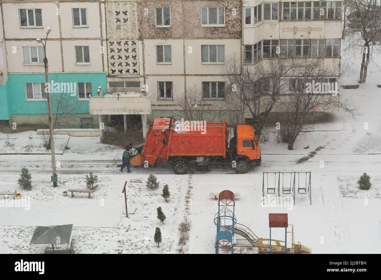Garbage truck workers. Garbage removal in residential area, garbage men loading household rubbish in garbage truck Stock Photo