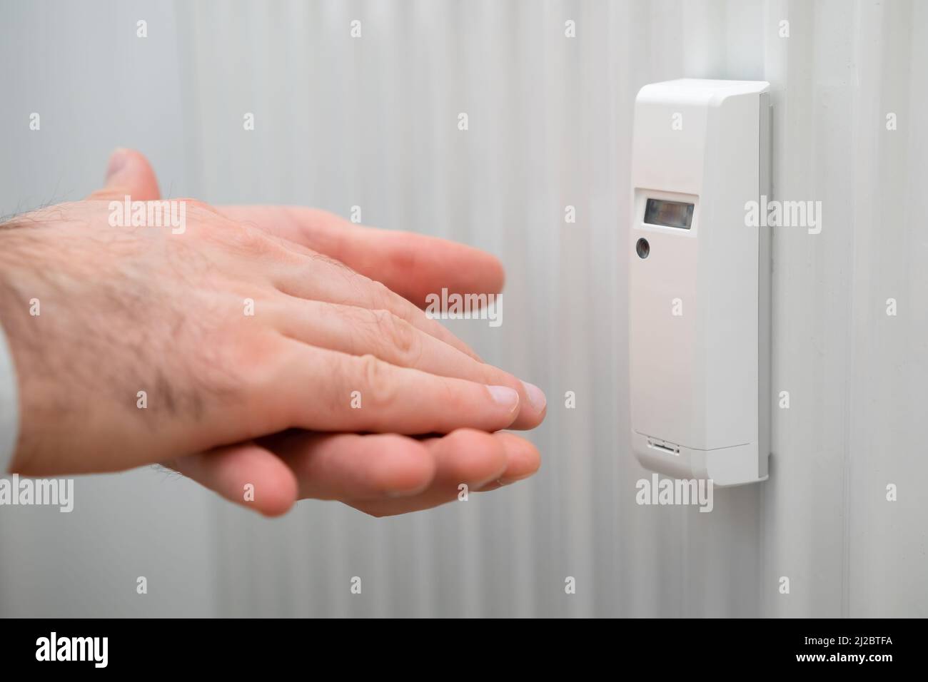Battery heat meter and man hands demonstrate cold battery. Raising heating and energy prices.  Stock Photo