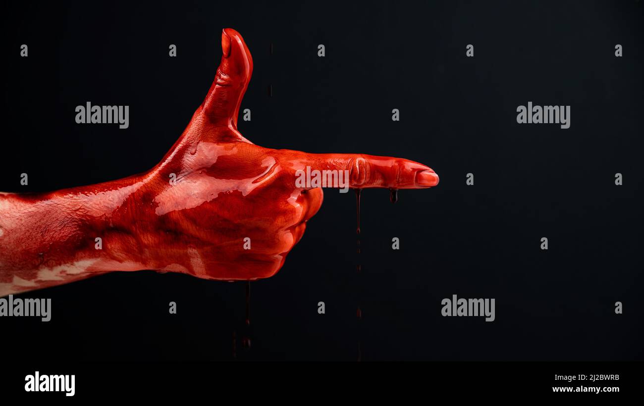 Woman's hand in blood shows a gesture of a gun on a black background.  Stock Photo