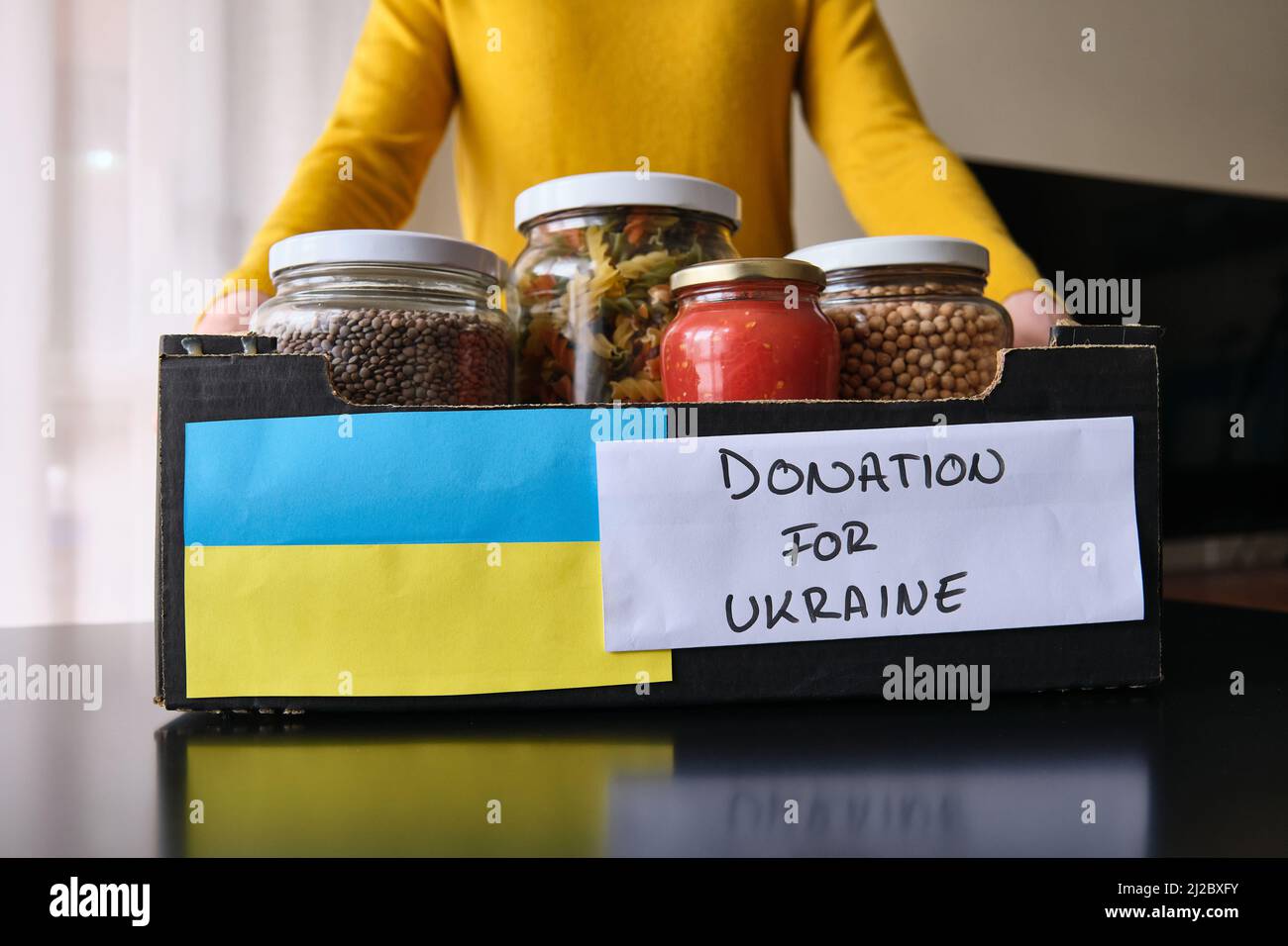 A Unrecognizable woman picking up a box of food to donate to Ukrainian