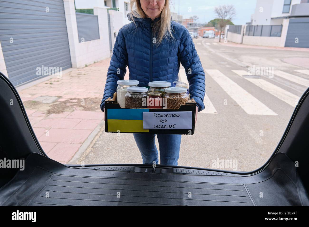Volunteer taking a box out of the car with donation food for Ukrainian
