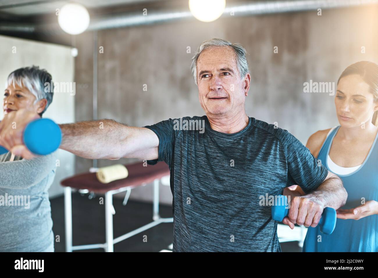 The power to live actively is in your hands. Shot of a senior man and woman using weights with the help of a physical therapist. Stock Photo