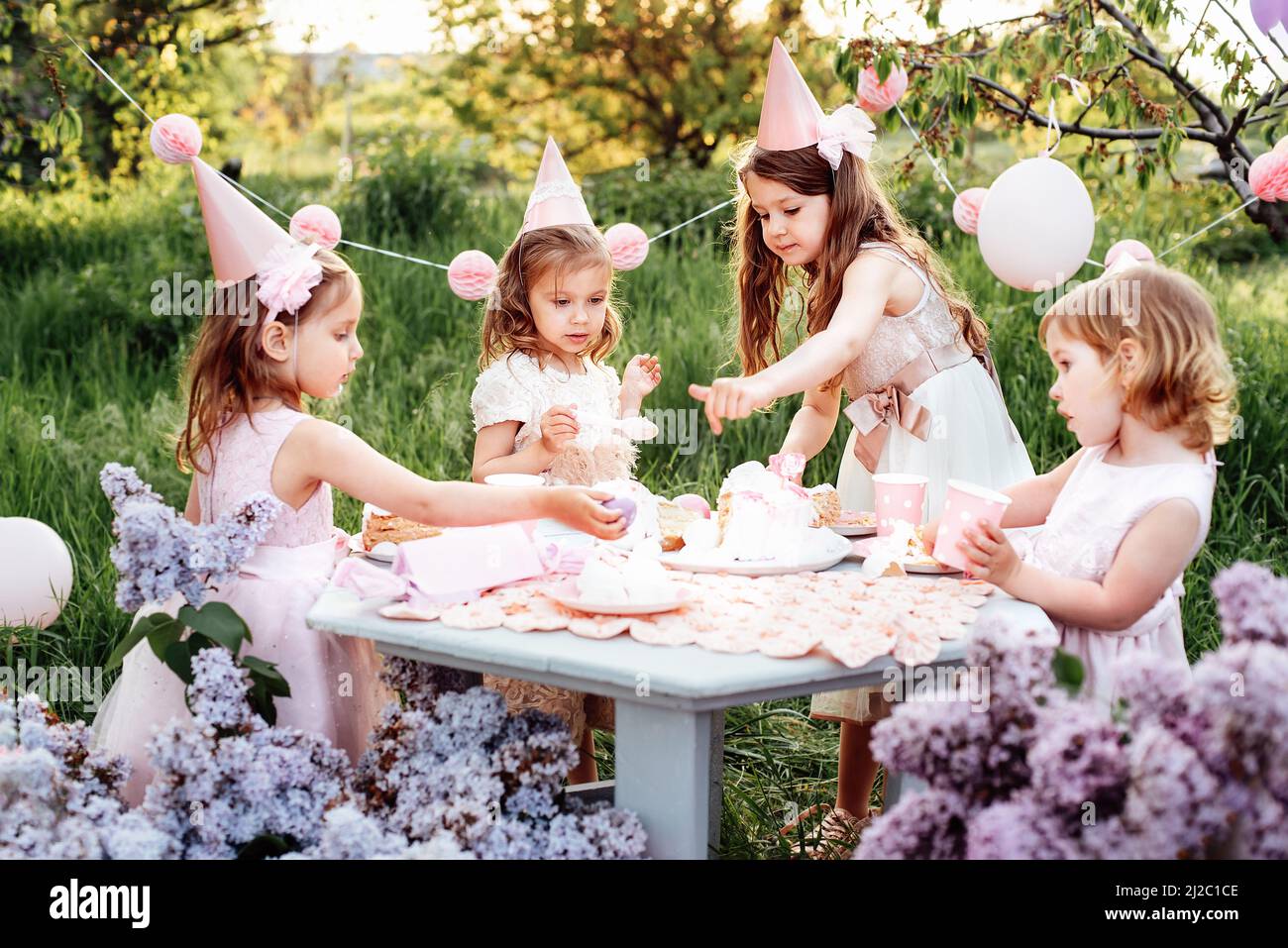 Summer outdoor kids birthday party. Group of happy Children celebrating  birthday in park. Children blow candles on birthday cake. Kids party lilac  pin Stock Photo - Alamy