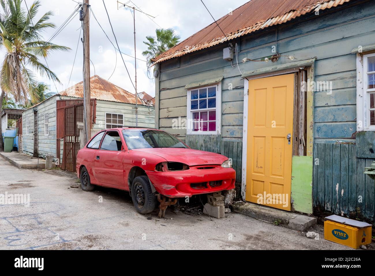 Side street with small weathered house and a broken red car in the ...