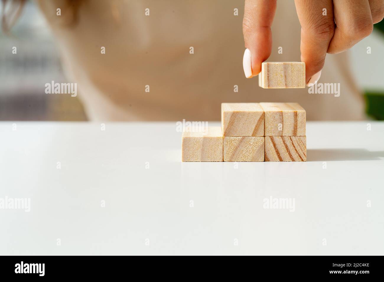 Hand arranging wood cube stacking as stair step shape Stock Photo - Alamy