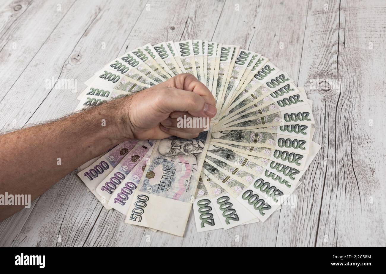 Czech banknotes in a fan and the hands of a merchant placed on them. Financial concept.Financial concept in Czech currency. business, finance, saving Stock Photo