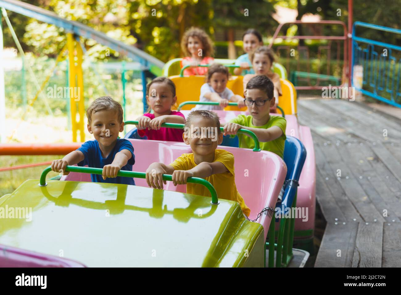 The happy kids on a roller coaster in the amusement park Stock Photo
