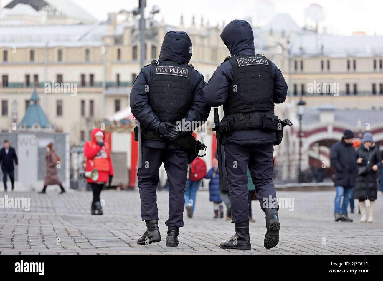 Russian police officers in bulletproof vests patrol a city street in Moscow at spring. Translation of inscription on the male backs: 'Police' Stock Photo