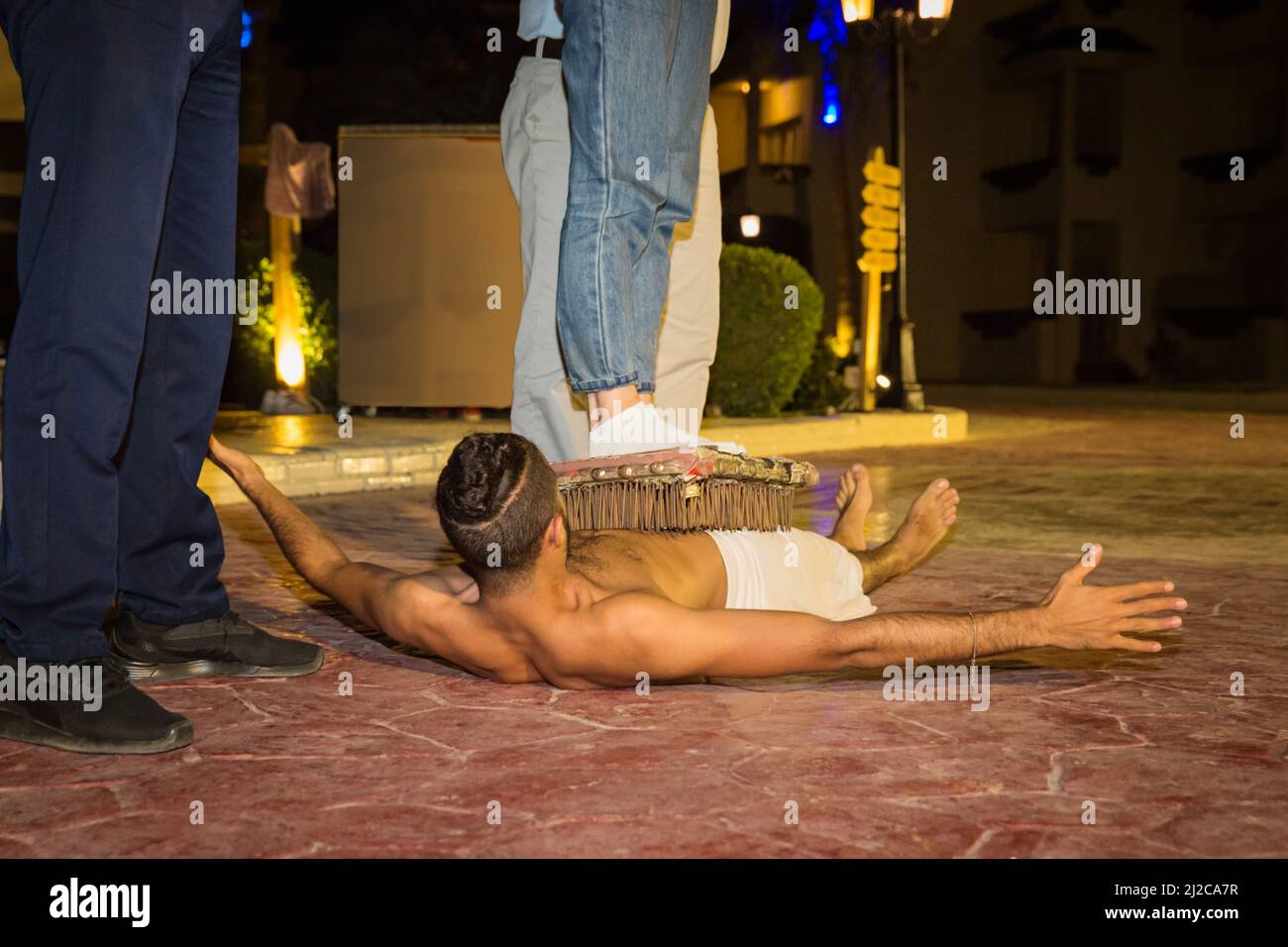 Actor fakir stuntman lies on a bed of nails without getting hurt. Stock Photo