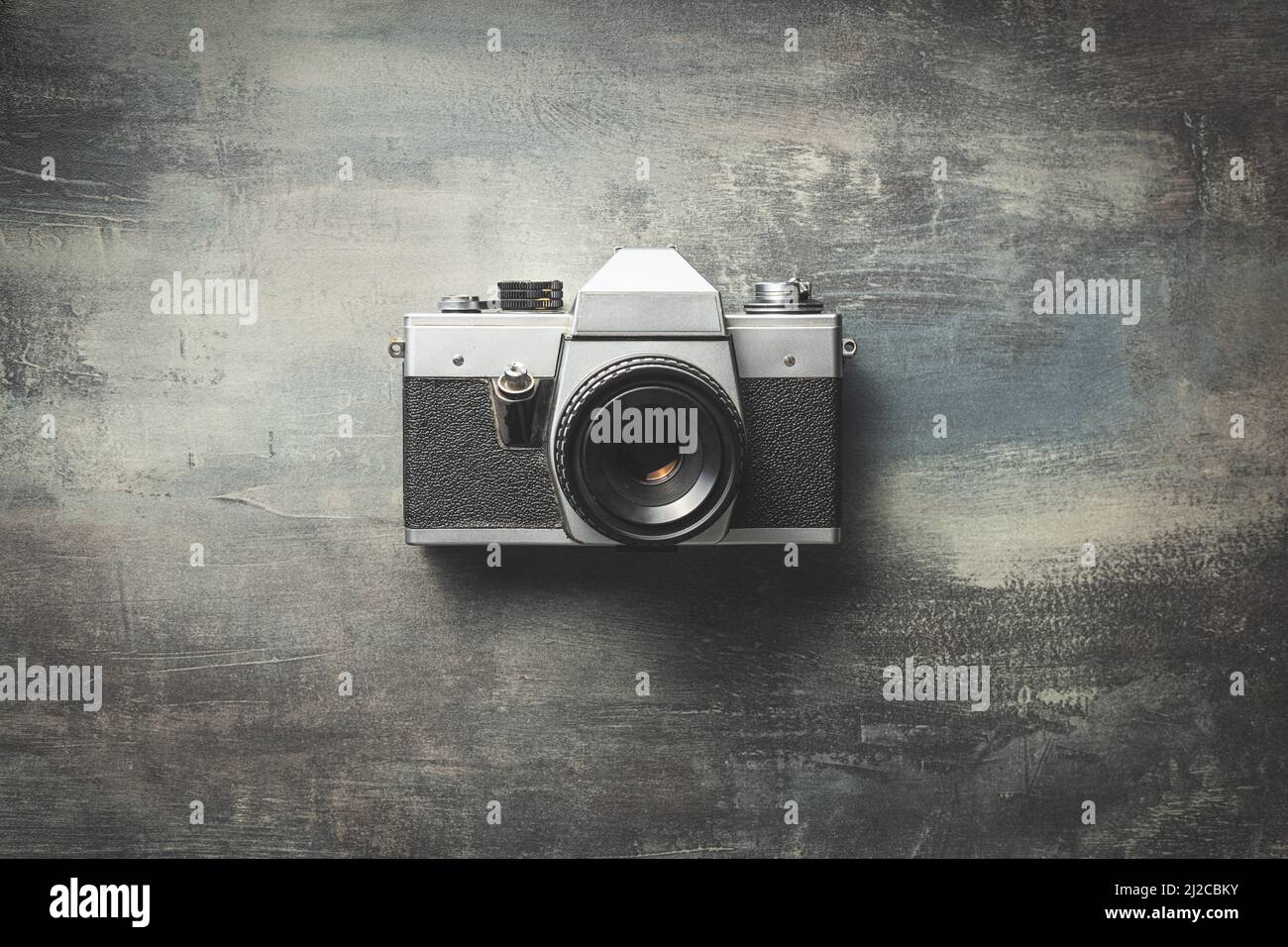 Retro analogue camera. Vintage old fashioned camera with lens on grunge background. Top view. Stock Photo
