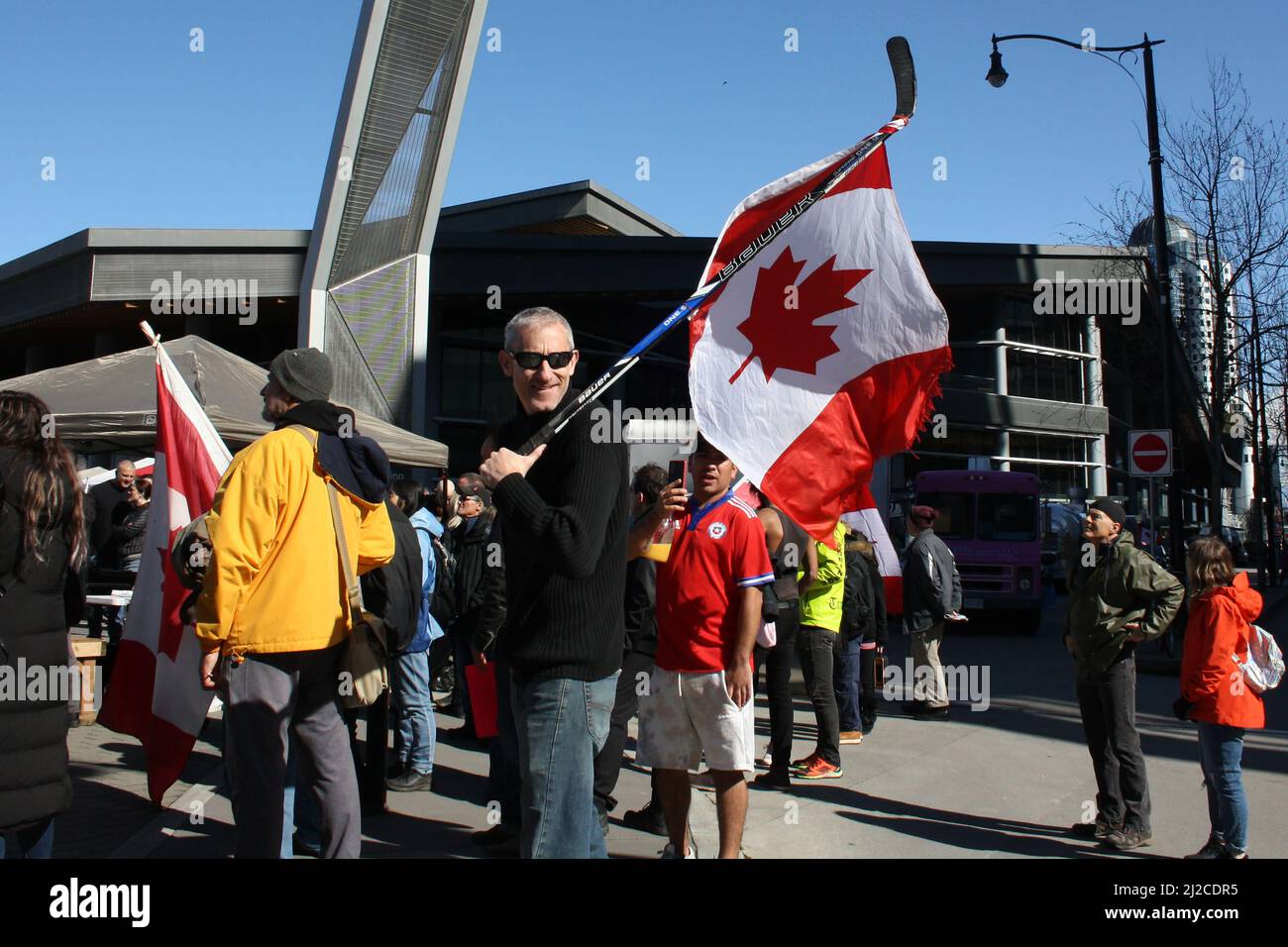 A Man carrying Canadian flag on ice hockey stick in downtown Vancouver