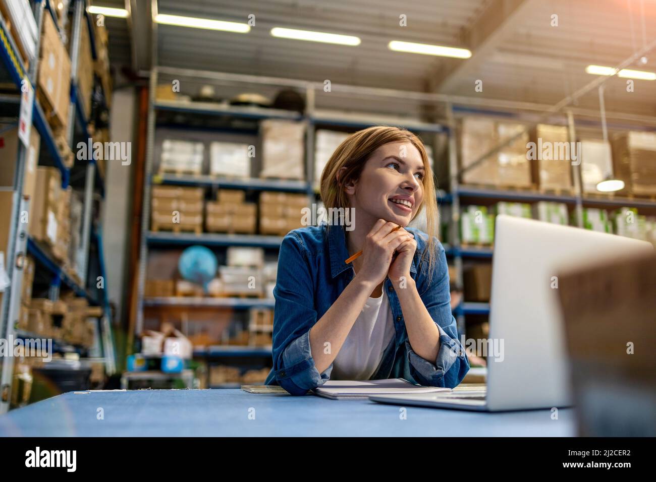 Woman using laptop at warehouse Stock Photo