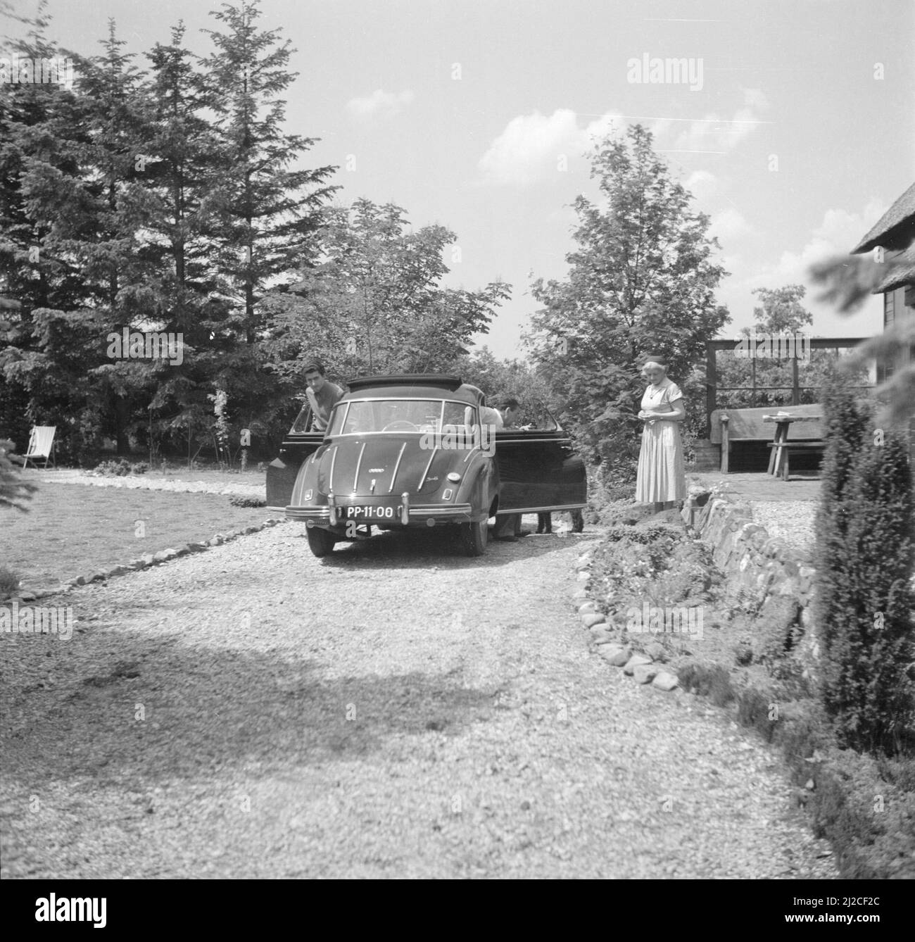 The conductor Eduard van Beinum arrives with his son Bart in an open DKW at his country house Bergsham in Garderen. His wife Sepha van Beinum-Janssen is waiting for them  ca: June 5, 1954 Stock Photo
