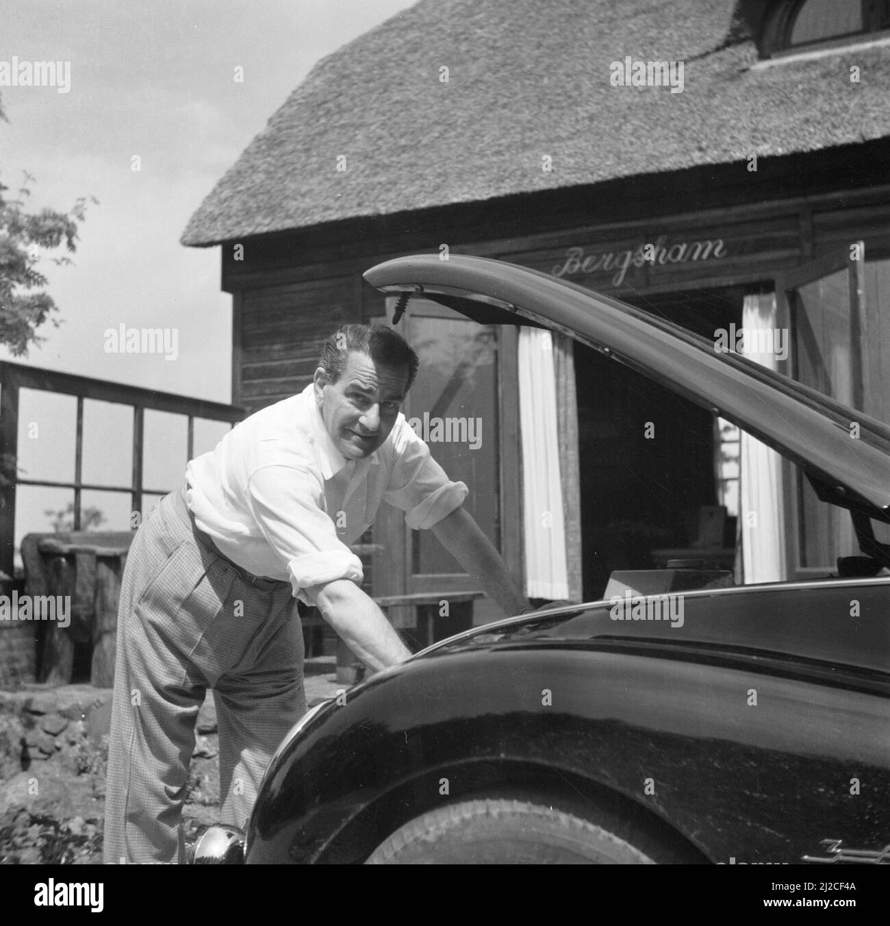 The conductor Eduard van Beinum looks under the hood of his open DKW at his country house Bergsham in Garderen. ca: June 5, 1954 Stock Photo
