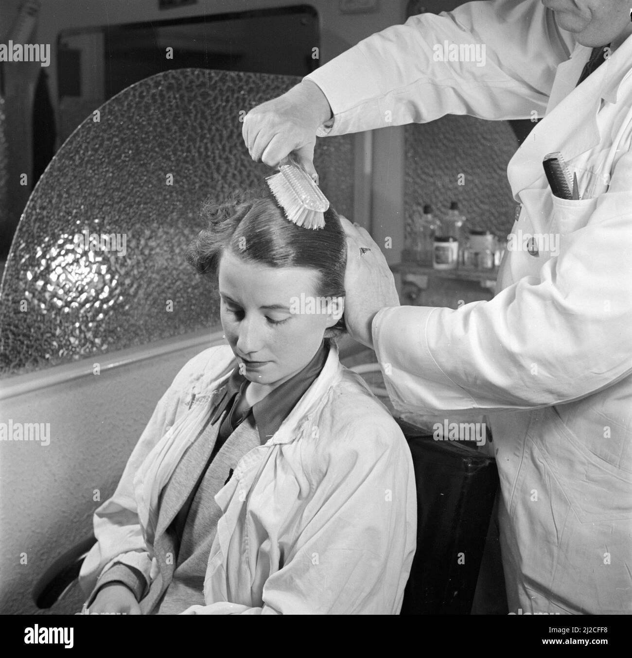 Woman sitting in a chair in a hair salon or beauty parlor ca. 1950
