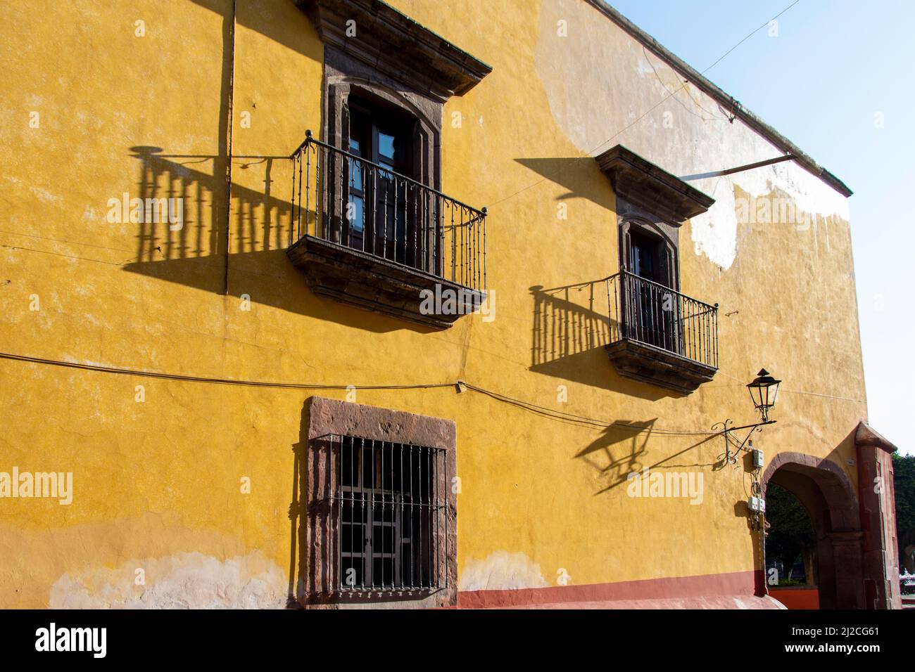 The side of a home painted yellow and features several wood framed ...