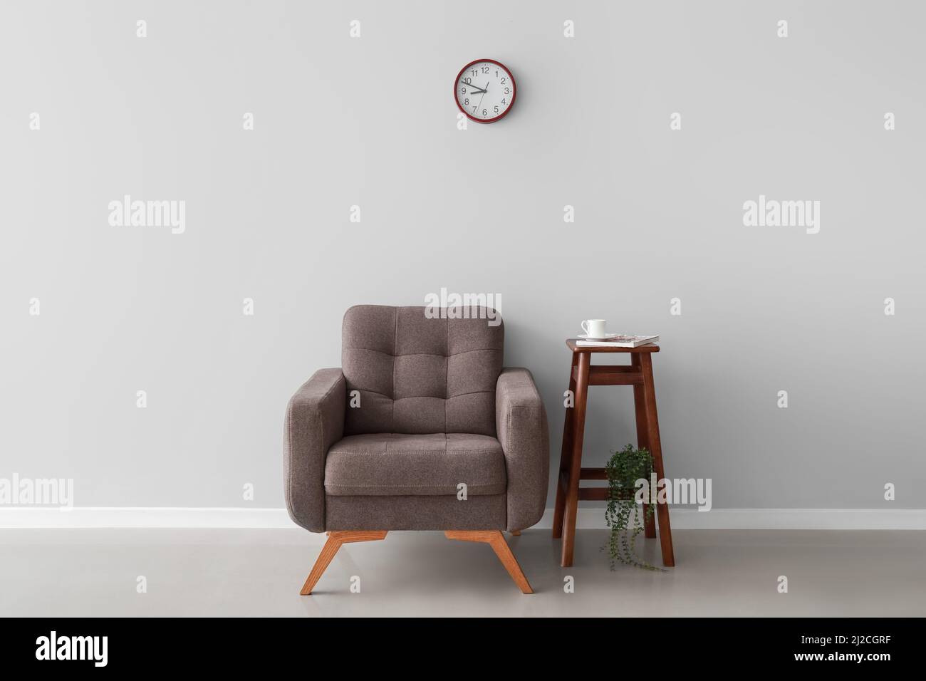 Interior of room with armchair and table near light wall Stock Photo ...