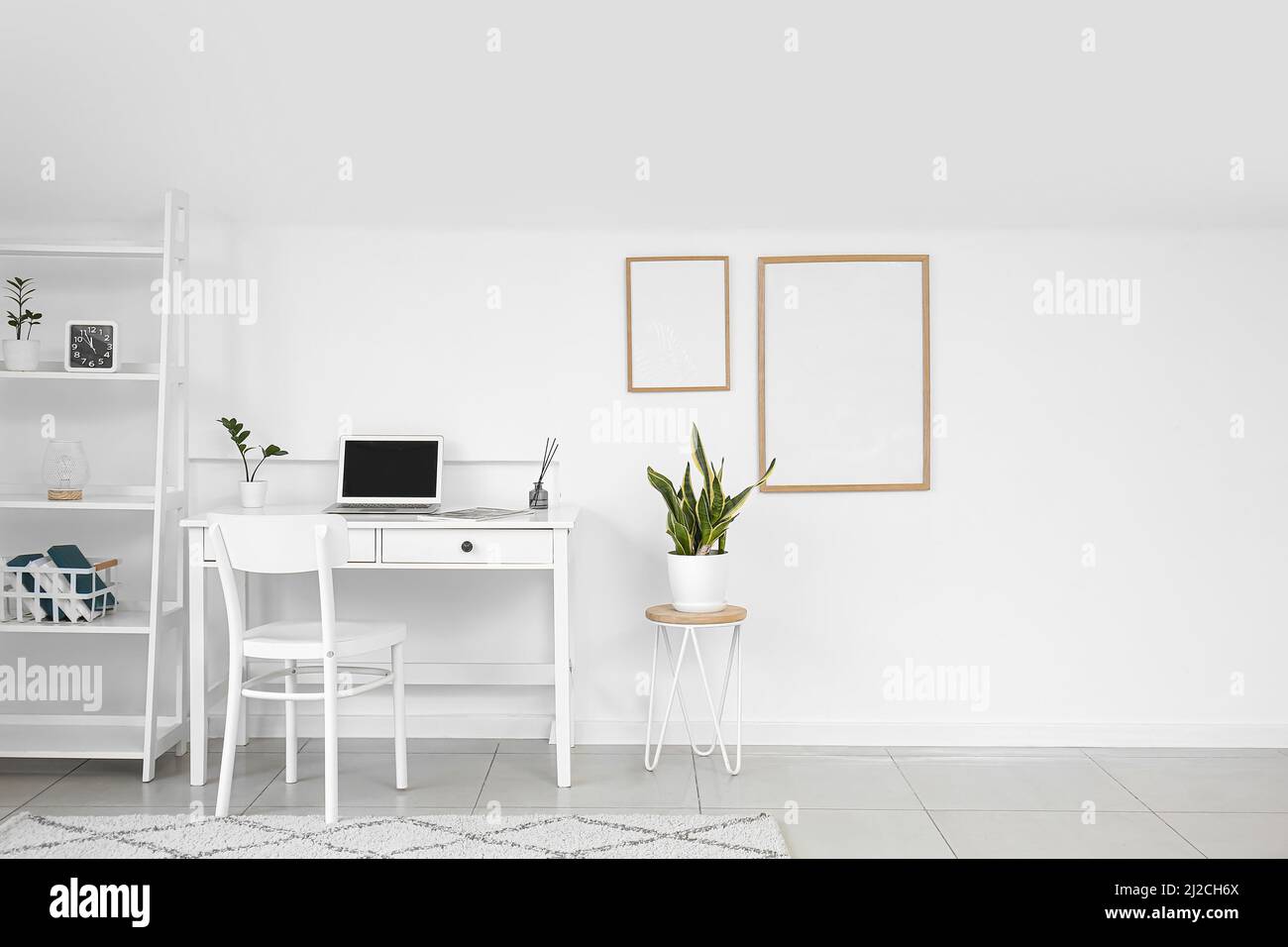 Interior of light room with modern workplace, shelving unit and frames