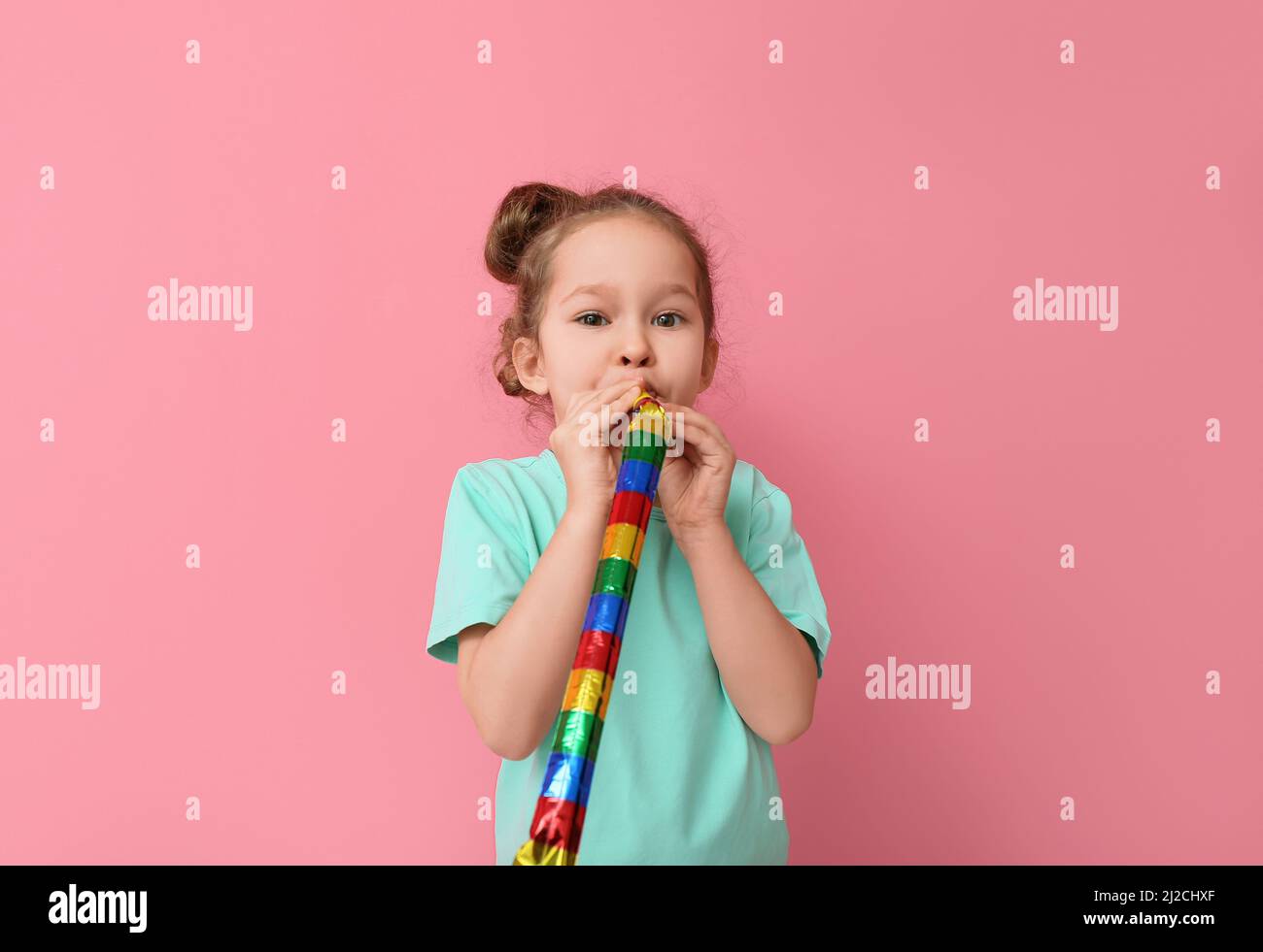 Funny little girl with party blower on color background. April fools ...
