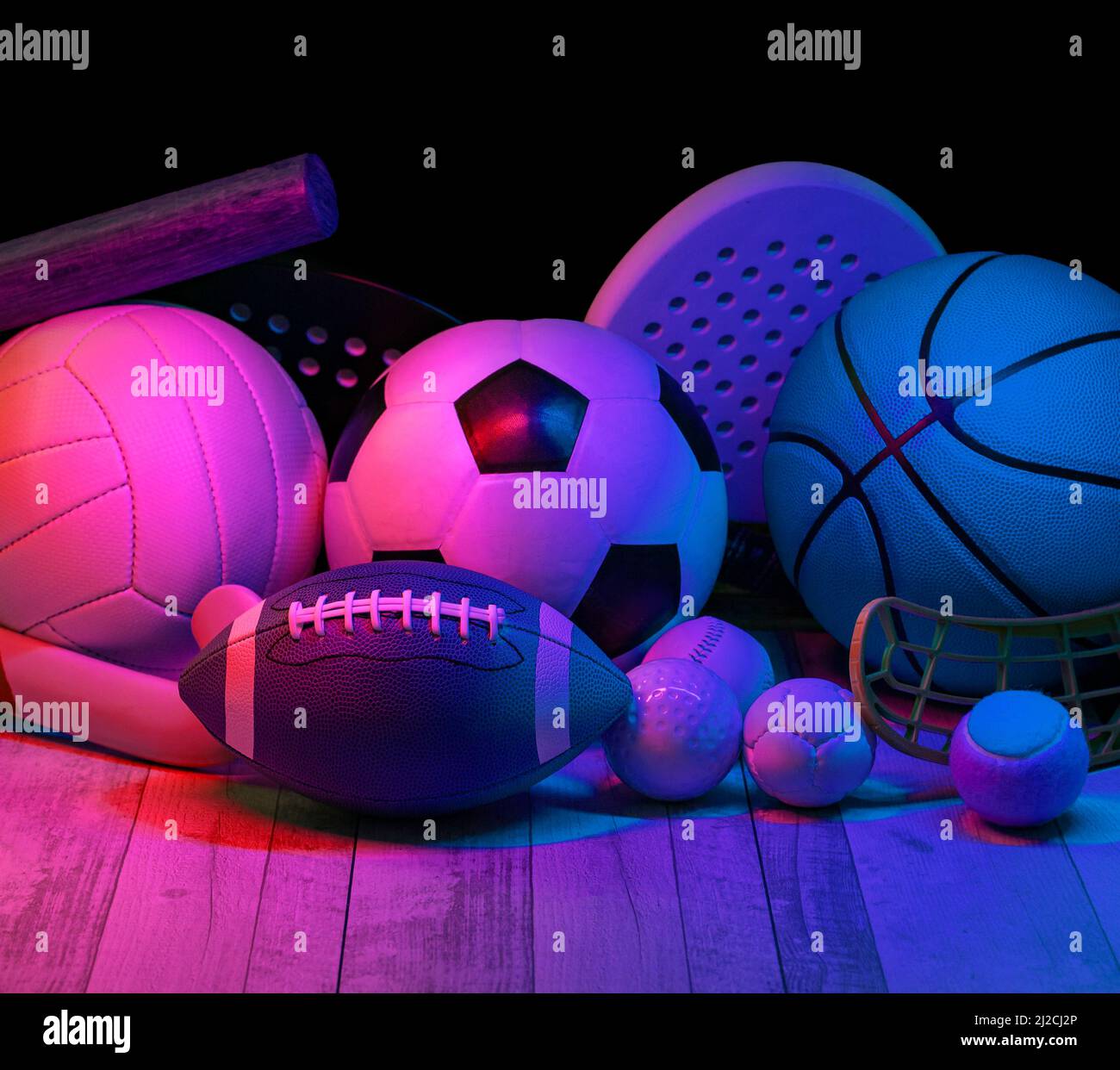 Sports equipment, rackets and balls on hardwood court floor with neon light background. Horizontal education and sport poster, greeting cards, headers Stock Photo
