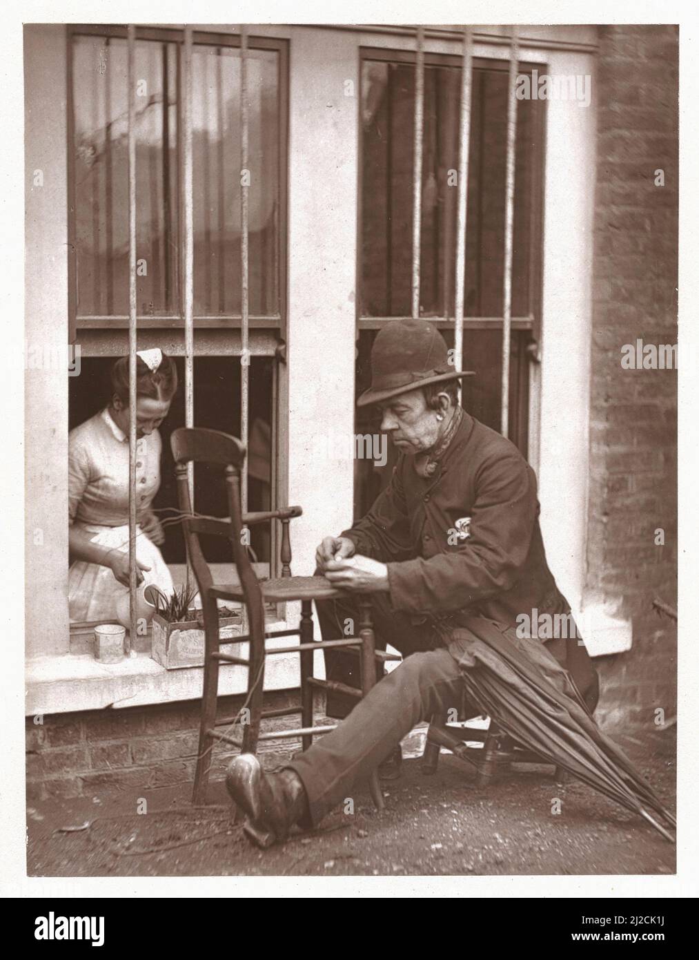 'Caney' The Clown,' 1877-78. Woodburytype print of a man repairing the cane seat of a chair. Photography by John Thomson (1837 - 1921). Stock Photo