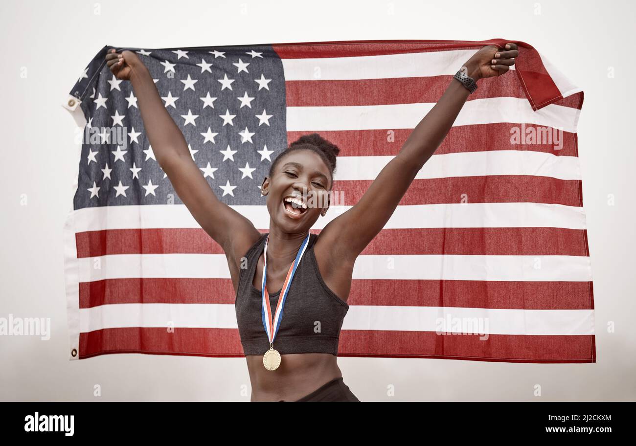 You can congratulate me now. Shot of a young female athlete celebrating her win while running with a flag. Stock Photo