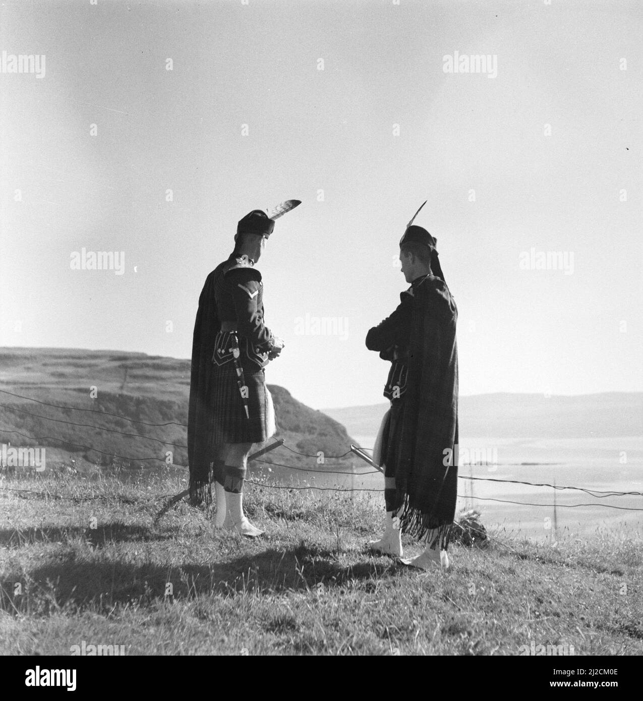 Two participants of the Highland Games look out over the sea ca: 1934 Stock Photo