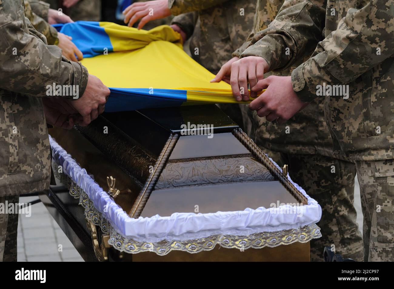 Lviv, Ukraine. 31st Mar, 2022. Ukrainian servicemen covering the coffin with Ukrainian flag during the burial. Funeral ceremony of 3 Ukrainian soldiers Kozachenko Andriy, Sarkisyan Ihor, Oliynyk Yuriy killed by Russian forces amid the Russian invasion in Lviv. (Credit Image: © Mykola Tys/SOPA Images via ZUMA Press Wire) Stock Photo
