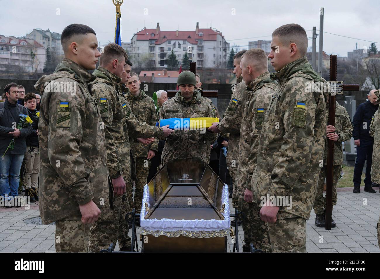 Lviv, Ukraine. 31st Mar, 2022. Ukrainian servicemen uncover the flag from a coffin during the burial. Funeral ceremony of 3 Ukrainian soldiers Kozachenko Andriy, Sarkisyan Ihor, Oliynyk Yuriy killed by Russian forces amid the Russian invasion in Lviv. (Credit Image: © Mykola Tys/SOPA Images via ZUMA Press Wire) Stock Photo