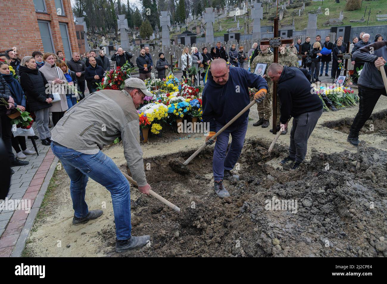 Lviv, Ukraine. 31st Mar, 2022. People seen covering the grave during the burial. Funeral ceremony of 3 Ukrainian soldiers Kozachenko Andriy, Sarkisyan Ihor, Oliynyk Yuriy killed by Russian forces amid the Russian invasion in Lviv. (Credit Image: © Mykola Tys/SOPA Images via ZUMA Press Wire) Stock Photo