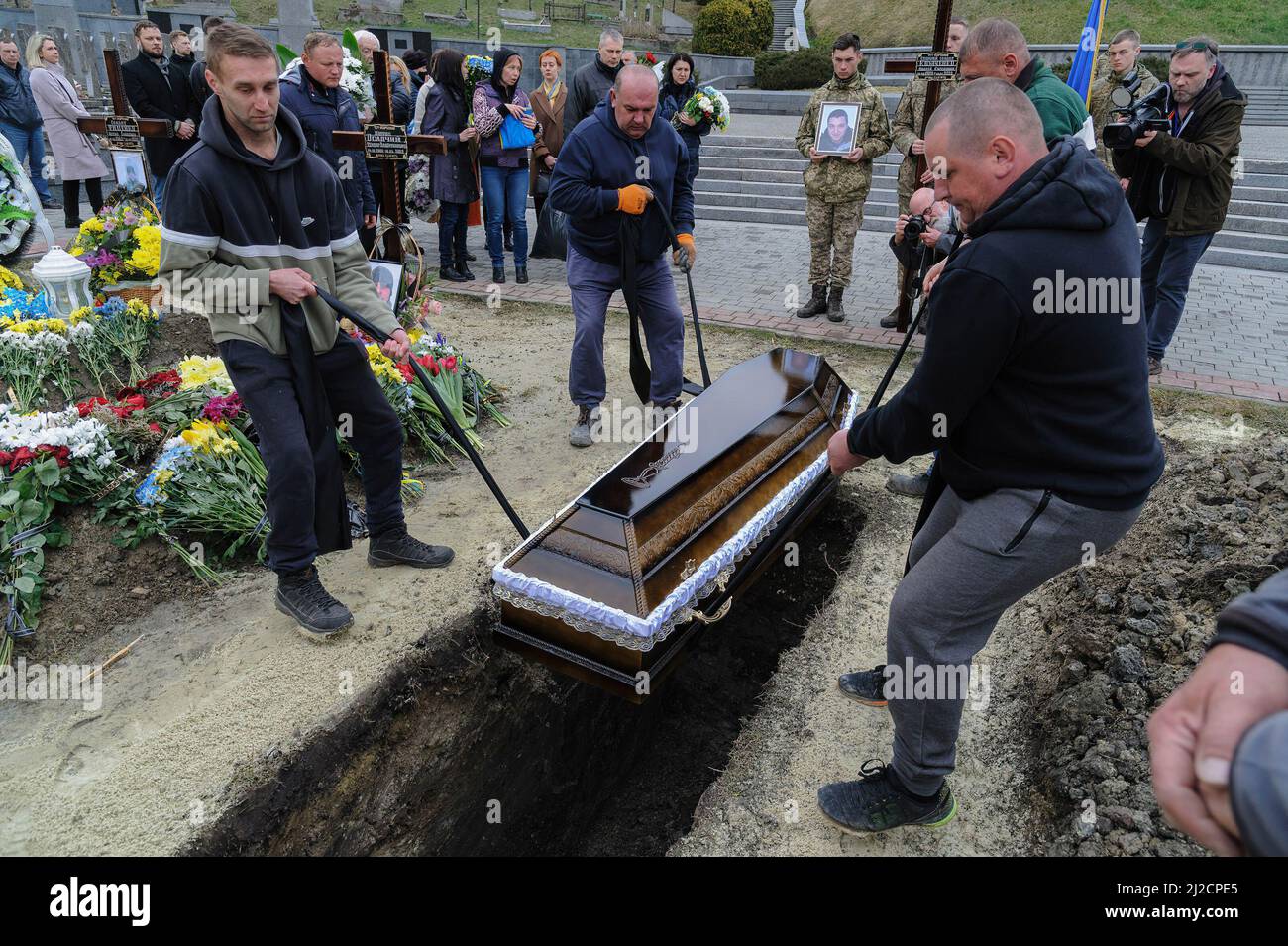 Lviv, Ukraine. 31st Mar, 2022. Men lowering a coffin into a grave during the burial. Funeral ceremony of 3 Ukrainian soldiers Kozachenko Andriy, Sarkisyan Ihor, Oliynyk Yuriy killed by Russian forces amid the Russian invasion in Lviv. (Credit Image: © Mykola Tys/SOPA Images via ZUMA Press Wire) Stock Photo