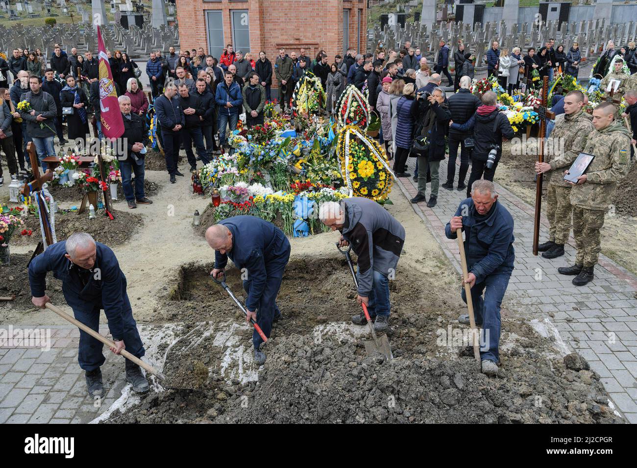 Lviv, Ukraine. 31st Mar, 2022. People seen covering the grave during the burial. Funeral ceremony of 3 Ukrainian soldiers Kozachenko Andriy, Sarkisyan Ihor, Oliynyk Yuriy killed by Russian forces amid the Russian invasion in Lviv. (Credit Image: © Mykola Tys/SOPA Images via ZUMA Press Wire) Stock Photo