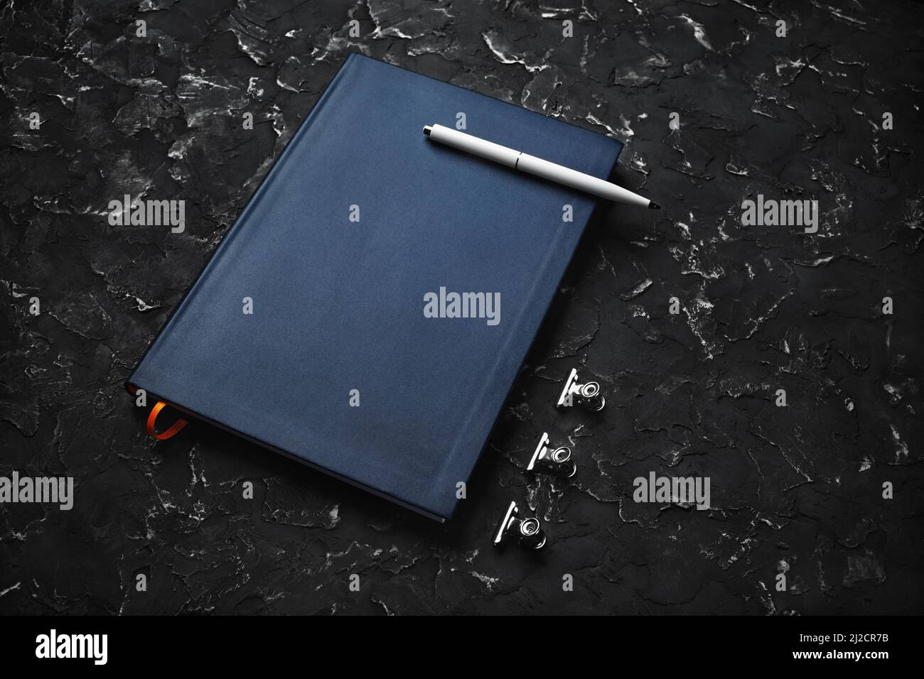 Blank blue notepad, pen and clips on black plaster background Stock ...