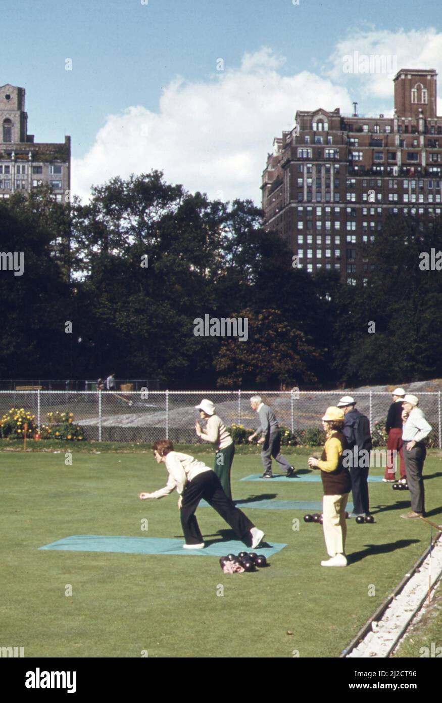 Members of the Bowling Green Bowling Club meet for a game in Central Park. The New York City department of parks waters the fine turf, and club members, who meet three times a week, tend a flower border themselves  ca.  1973 Stock Photo