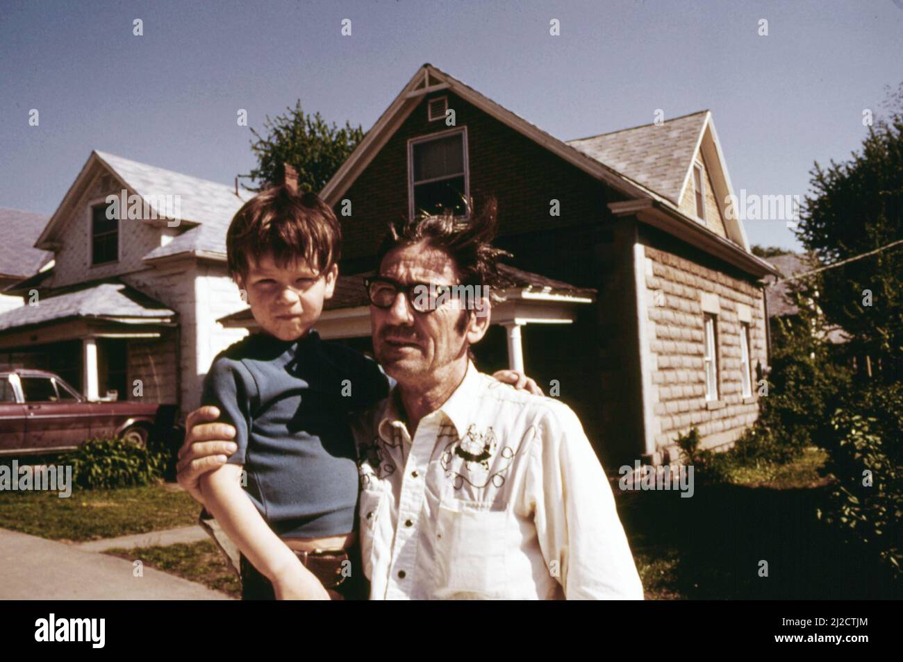 Ernest Watkins, a biscuit company employee, and son, stand outside the home his family has just rented  ca.  1975 Stock Photo